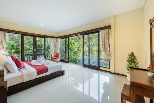 a bedroom with a bed and a desk and windows at Mardika Private Villa in Ubud