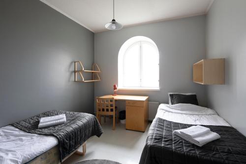 een slaapkamer met 2 bedden, een bureau en een raam bij Opiston Kunkku in Lahti