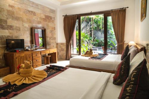 a hotel room with two beds and a television at Alam Terrace Cottages in Ubud