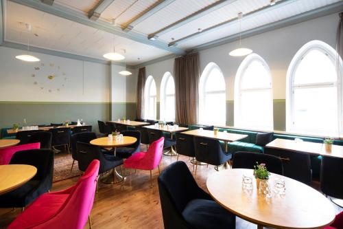 a dining room with tables and chairs and windows at Opiston Kunkku in Lahti