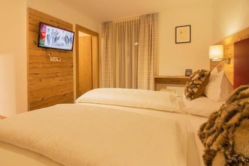 a bedroom with a white bed and a television at Haus Flexen rooms & apartments in Stuben am Arlberg