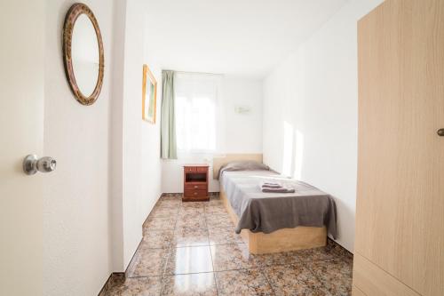 een kleine slaapkamer met een bed en een spiegel bij CUNIT HOME in Cunit