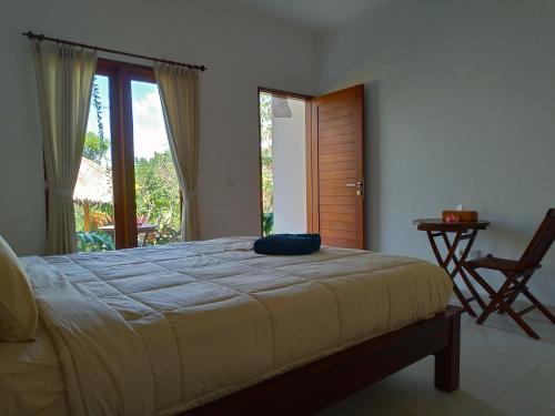 a bedroom with a bed and a large window at Lala Homestay Bingin in Uluwatu