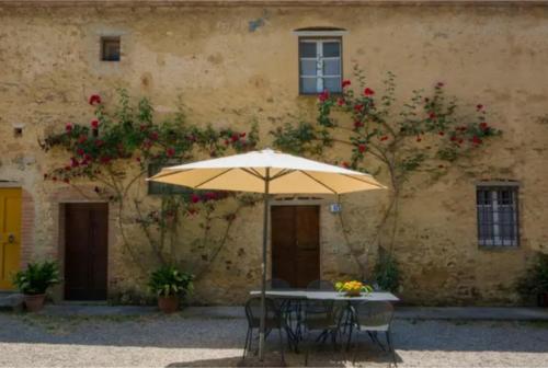a table with an umbrella in front of a building at Agriturismo La Moraia in Poggibonsi