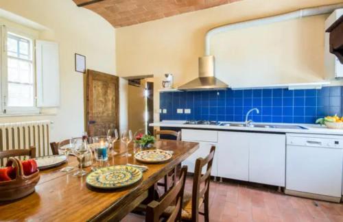 a kitchen with a wooden table and a kitchen with blue tiles at Agriturismo La Moraia in Poggibonsi