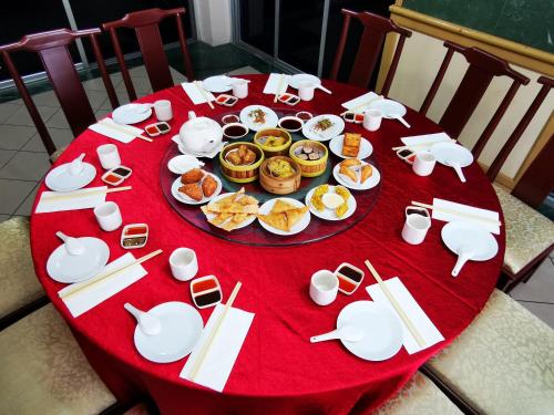 a table with a red table cloth with food on it at Hotel Sandakan in Sandakan