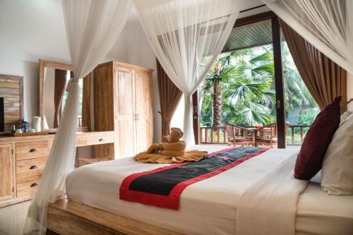 a bedroom with a bed with a teddy bear sitting on it at Alam Terrace Cottages in Ubud