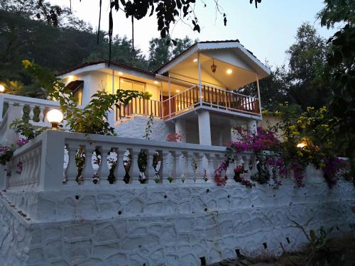 a white house with a white fence and flowers at WhiteHouse Homestay by Oxystays Hospitality in Alibaug