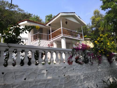 a white house with flowers on a fence at WhiteHouse Homestay by Oxystays Hospitality in Alibaug