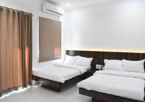 een kamer met 2 bedden en een raam bij Hotel President Banquet & Lawn in Aurangabad