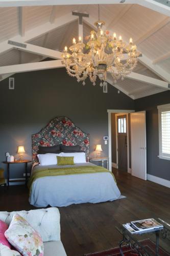 a bedroom with a large bed and a chandelier at Luxurious Escape,Matakana in Matakana