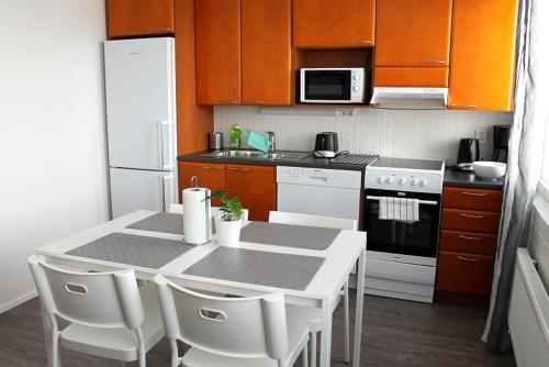 a kitchen with a white table and white appliances at Kotimaailma Apartments Joensuu - Koskikatu 11 in Joensuu