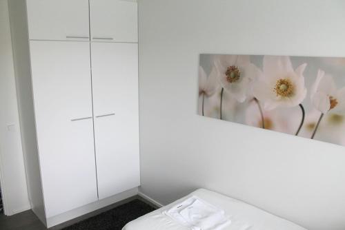 a bedroom with white cabinets and a painting on the wall at Kotimaailma Apartments Joensuu - Koskikatu 11 in Joensuu