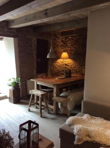 a dining room with a table and a stone wall at Petite maison d'Amelotte in Sainte-Cécile