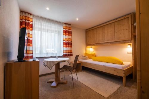 a bedroom with a bed and a desk and a television at Landhaus Gasser in Wenns