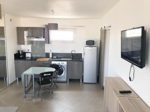 une cuisine avec une petite table et une cuisine avec une télévision dans l'établissement BEAU STUDIO CLIMATISE Rive Gauche, à Palavas-les-Flots