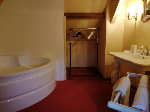 a bathroom with a tub and a sink at Aux Trois Damoiselles in Beuvron-en-Auge