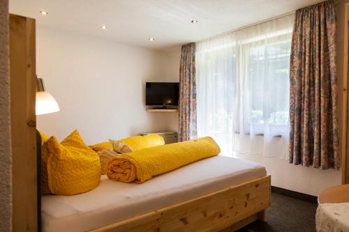 a room with a bed with yellow pillows and a window at Landhaus Gasser in Wenns