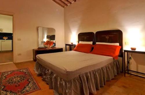a bedroom with a bed with orange pillows and a mirror at Agriturismo La Moraia in Poggibonsi