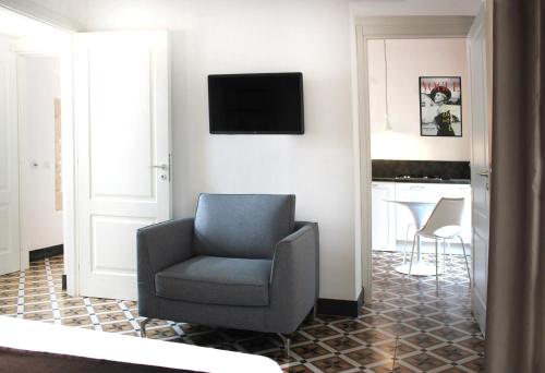 a living room with a chair and a television on a wall at Isabella di Castiglia Apartments in Siracusa