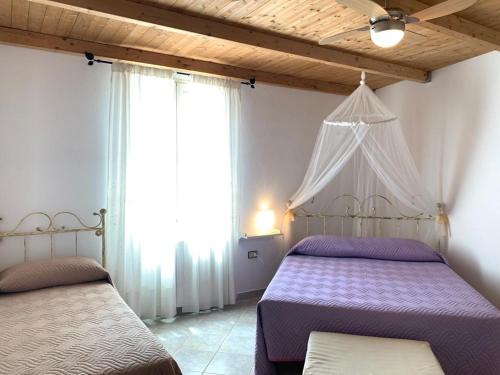 1 dormitorio con 2 camas y ventana en B&B S'Incontru, en Galtellì