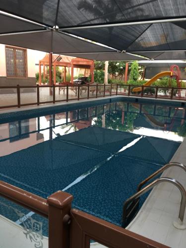 uma piscina com uma mesa de pingue-pongue e um guarda-sol em The Coral House em Jeddah