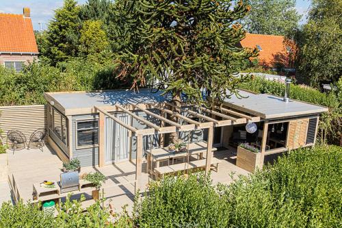 a small house with a deck in a garden at LODGES 7Huizen aan Zee in Scharendijke