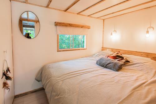 a bedroom with a bed with a mirror and a window at LODGES 7Huizen aan Zee in Scharendijke