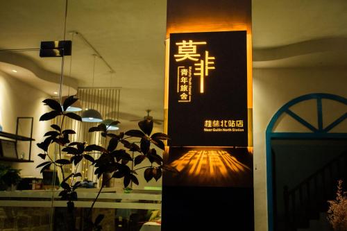 a sign on a wall in a room with a plant at Murphy Youth Hostel Guilin桂林北站莫非青年旅舍 in Guilin
