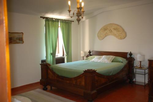 a bedroom with a bed with green sheets and a window at Agriturismo Le Volte in Mocaiana
