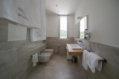 a white bathroom with a sink and a toilet at Capo Torre Resort & SPA in Albisola Superiore