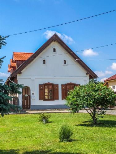 ein weißes Haus mit braunen Türen und einem grünen Garten in der Unterkunft Tulipános vendégház in Fertőszentmiklós