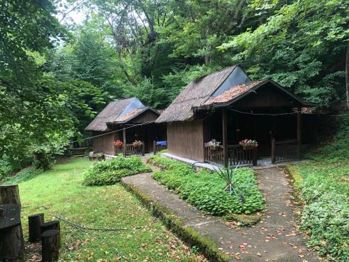 two wooden huts in a yard with trees at Hotel Saint Nedelya in Kolarovo