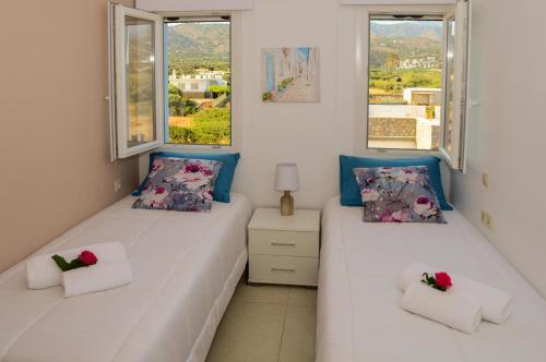 two beds in a room with two windows at Meltemi Beach Apartments in Milatos