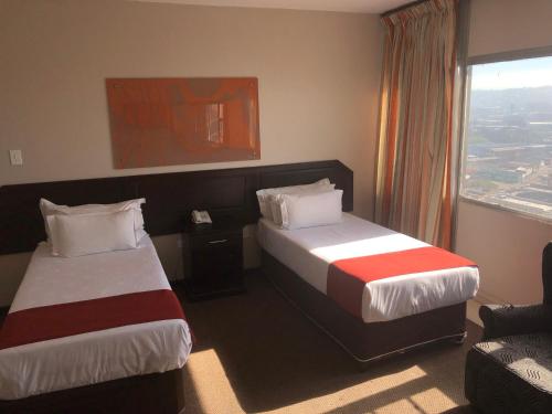 a hotel room with two beds and a window at Coastlands Durban Self Catering Holiday Apartments in Durban