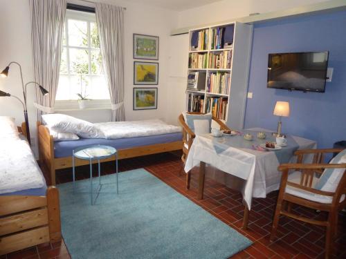 a room with a bed and a table and a tv at Ferienwohnung Landhaus im Grünen in Bad Zwischenahn
