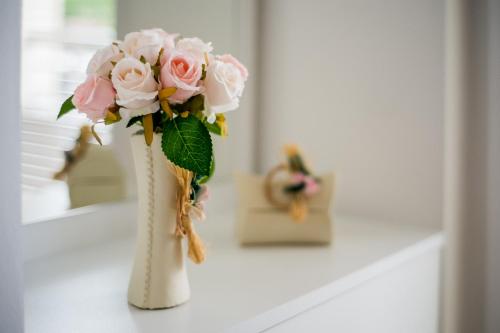 a white vase filled with pink roses on a table at Enjoy Apartments Karamach in Ohrid