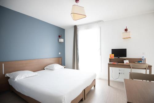 - une chambre avec un lit, un bureau et une télévision dans l'établissement Zenitude Hôtel-Résidences Narbonne Centre, à Narbonne