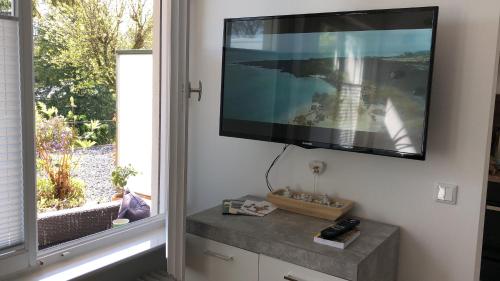 TV de pantalla plana colgada en una pared junto a una ventana en LITZI Apartment, en Baden-Baden