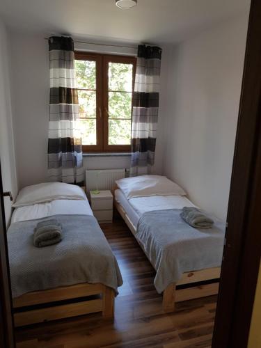 two twin beds in a room with a window at Apartament Nad Łomnicą in Karpacz