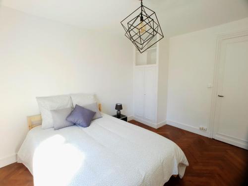 a bedroom with a white bed and a chandelier at Au 36, Les Apparts Hotel Joigny in Joigny
