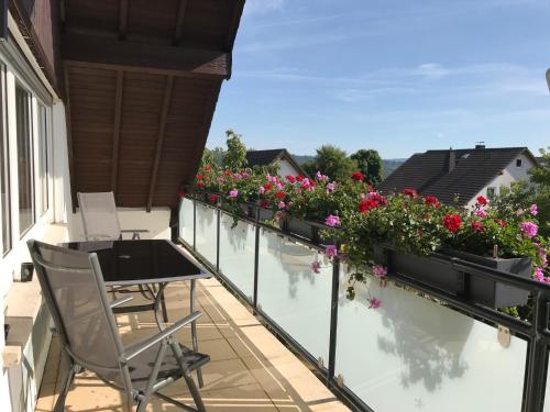 a balcony with flowers and a table and chairs at Ferienwohnung Vetter in Weisel