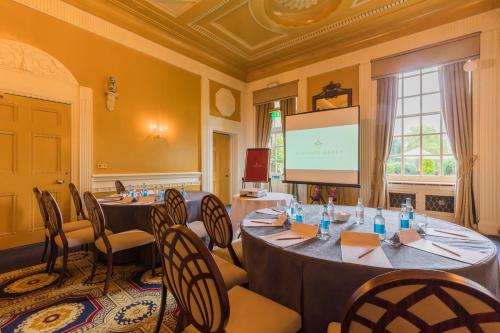 a meeting room with tables and chairs and a screen at Coombe Abbey Hotel in Coventry