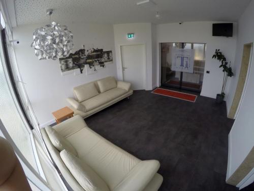 a living room with two white couches and a chandelier at Hotel Terminal One in Sindelfingen