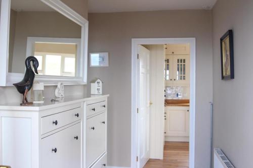 uma cozinha com armários brancos e um espelho em Atlantic Rose Cottage em Doolin