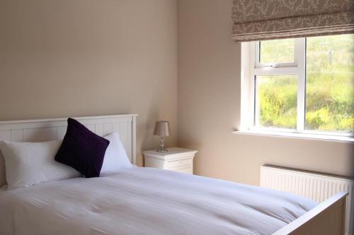 sypialnia z białym łóżkiem i oknem w obiekcie Atlantic Rose Cottage w mieście Doolin