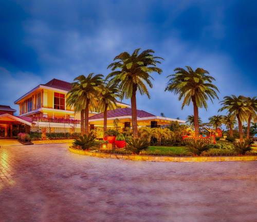 a building with palm trees in front of it at MAYFAIR Lake Resort in Raipur