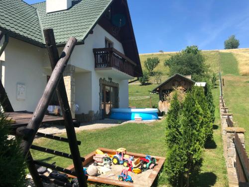 a house with a yard with toys in a sandbox at Pokoje U Moniki in Grywałd