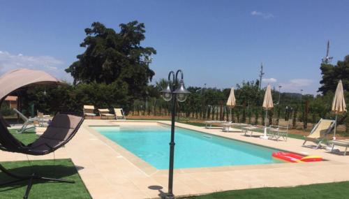 a swimming pool with a chair and a light pole at Poggio Picchio in Bibbona