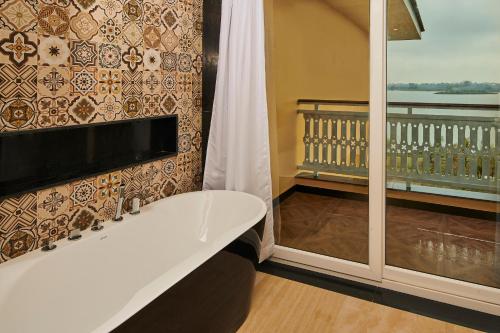 a bathroom with a bath tub and a balcony at MAYFAIR Lake Resort in Raipur